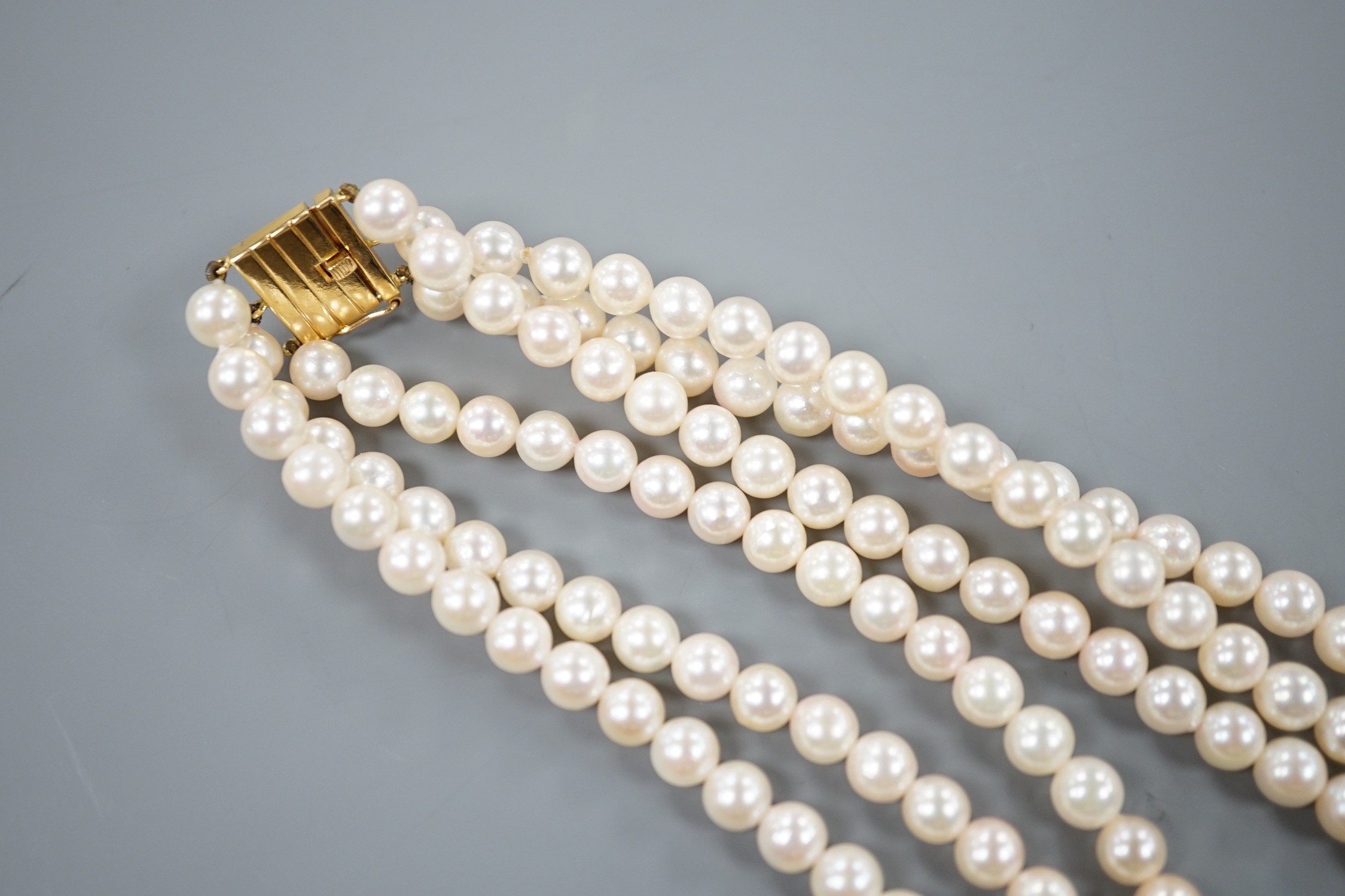 A triple strand cultured pearl necklace with 750 yellow metal clasp, 32cm.